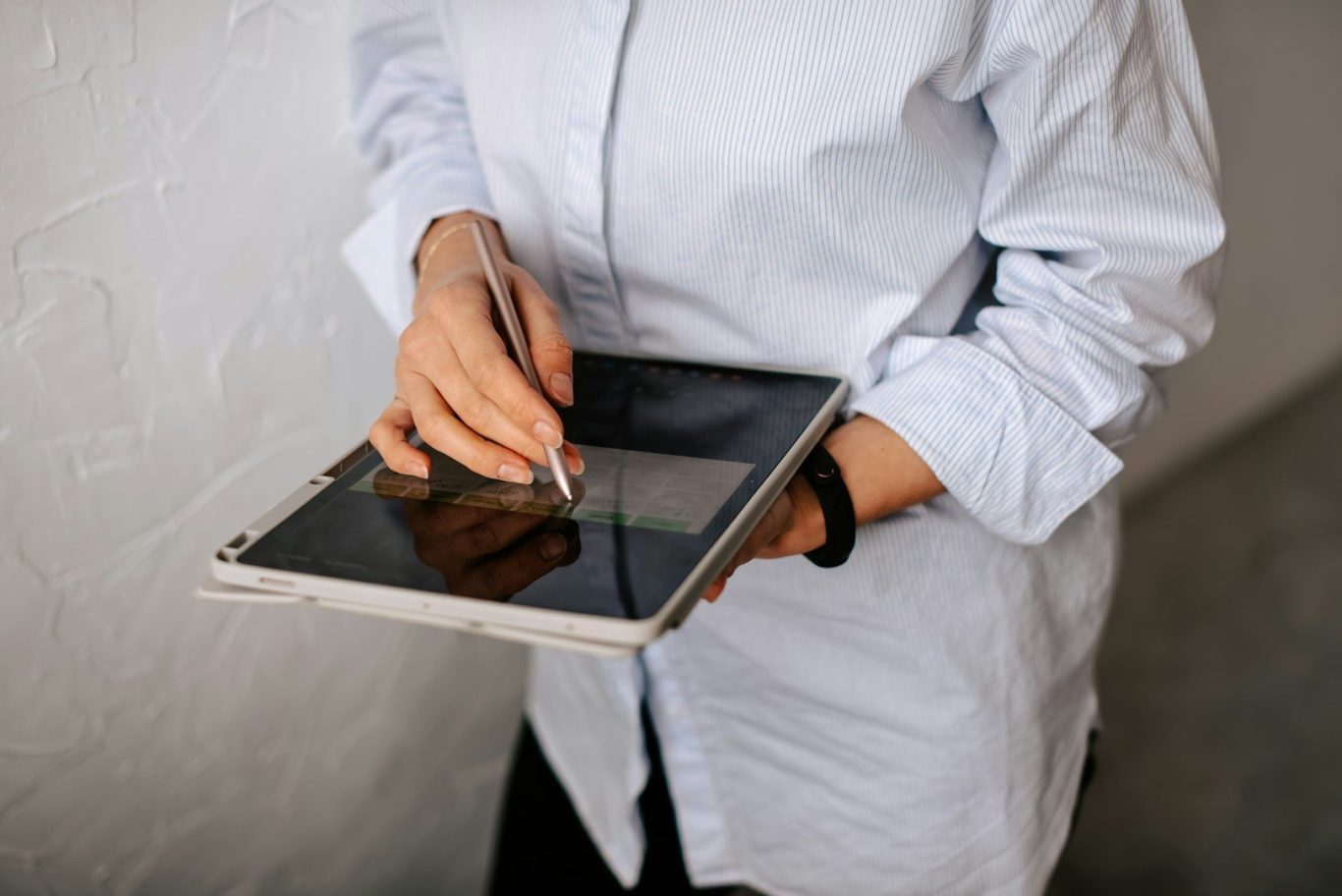 Tablet work A person wearing a light shirt uses a stylus on a tablet.